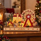 Villaggio natalizio luminoso con ruota panoramica e casette in legno, ambientato su un mobile tra decorazioni natalizie