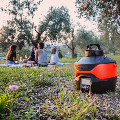 Famiglia riunita all’aperto durante un picnic con nebulizzatore Geyser in funzione sul prato