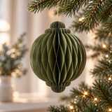 Pallina di Natale verde oliva in carta pieghettata appesa all’albero tra luci natalizie calde