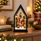 Lanterna natalizia con Babbo Natale e lampione tra abeti illuminati, ambientata in una casa decorata per Natale