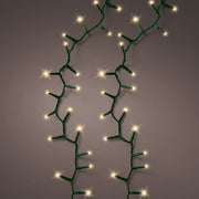 Fili di luci LED bianco caldo effetto sparkle can cavo verde accese su fondo scuro.