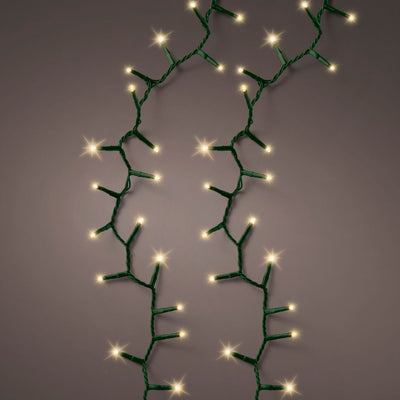 Fili di luci LED bianco caldo effetto sparkle can cavo verde accese su fondo scuro.