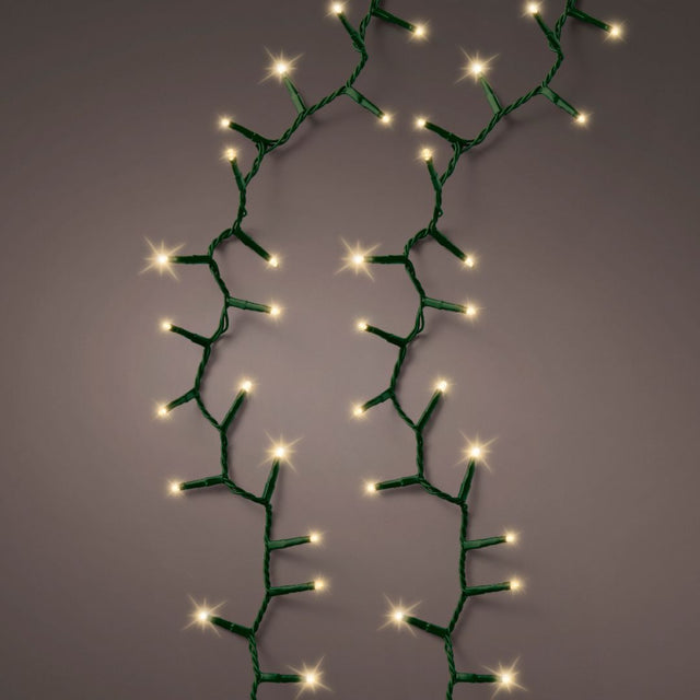 Fili di luci LED bianco caldo effetto sparkle can cavo verde accese su fondo scuro.