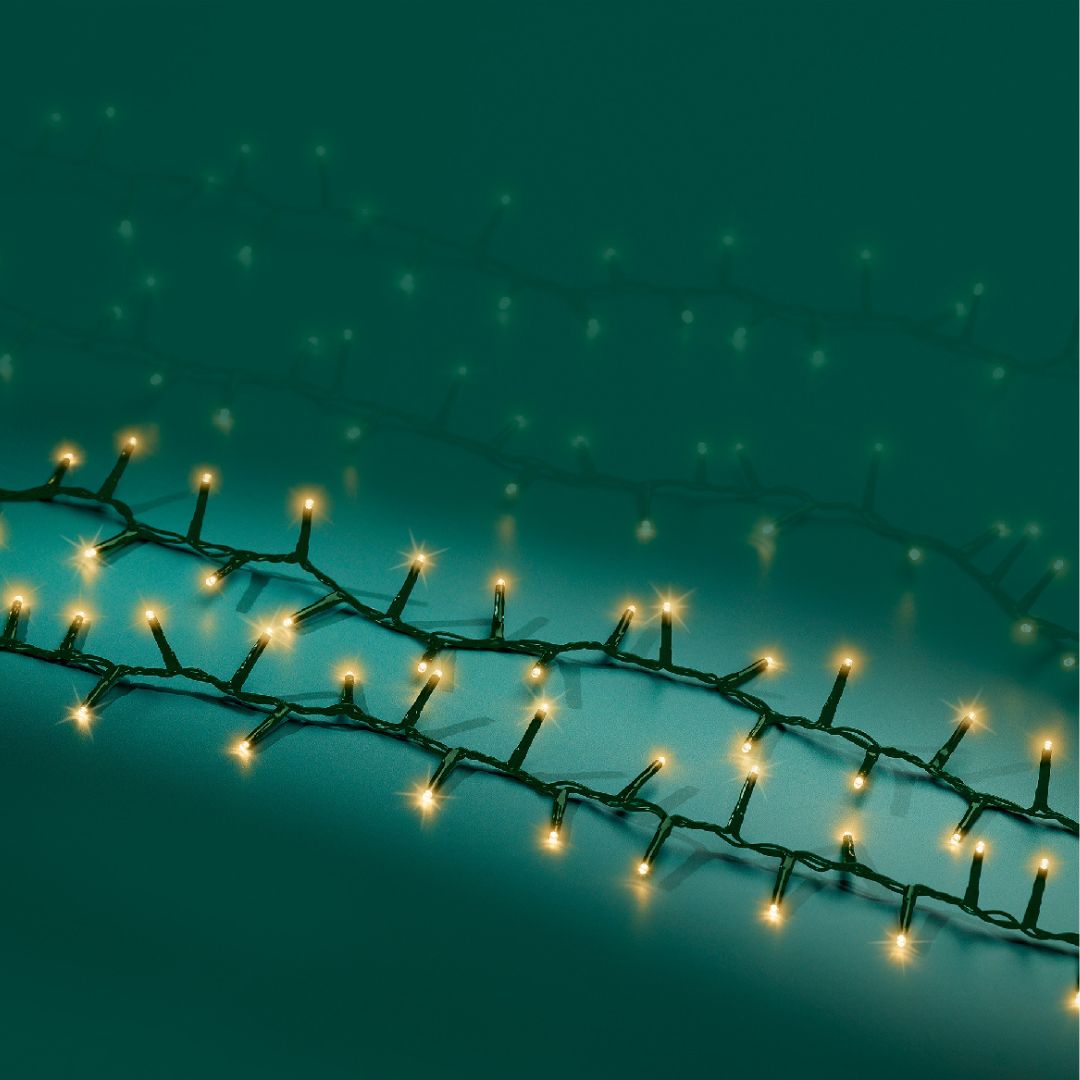 Fili di luci LED bianco caldo effetto sparkle con cavo verde su fondo turcehse.