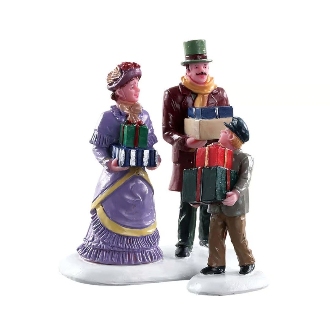 Personaggi Lemax con donna, uomo e bambino in abiti invernali mentre trasportano pacchi regalo natalizi.