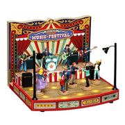Scena Lemax con palco musicale natalizio, band dal vivo, pubblico che balla e illuminazione decorativa in stile luna park.