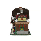 Coffee Klatch Lemax visto di lato, con tetto innevato, insegna della caffetteria, finestra illuminata e tenda a righe rosse e verdi.