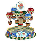 Giostra Lemax con mongolfiere colorate sospese attorno a una colonna centrale, cestelli con passeggeri e base circolare illuminata con insegne decorative.