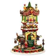 Torre natalizia Lemax decorata con schiaccianoci, campane, regali e albero di Natale, con conto alla rovescia dei giorni fino a Natale e trenino alla base.