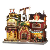 Edificio natalizio Lemax illuminato con cioccolateria, caffetteria di Mrs. Claus, dettagli innevati, decorazioni festive e meccanismi visibili nella parte superiore.
