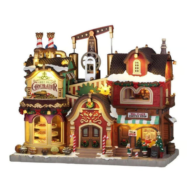 Edificio natalizio Lemax illuminato con cioccolateria, caffetteria di Mrs. Claus, dettagli innevati, decorazioni festive e meccanismi visibili nella parte superiore.