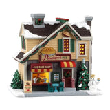 Penelope’s Pies Lemax, negozio di torte natalizio innevato e illuminato, con banco vendita, insegne, alberi decorati e pupazzo di neve.