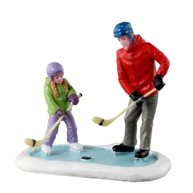 Padre e figlia che giocano a hockey insieme su una piccola superficie ghiacciata.