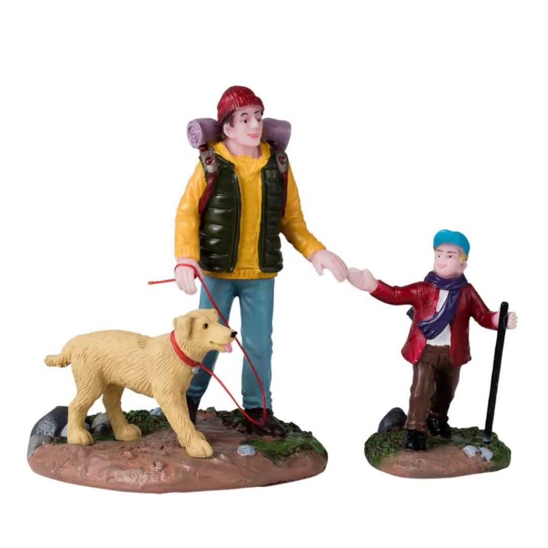 Escursionista, bambino e cane durante una passeggiata, con zaino, bastone da trekking e guinzaglio.