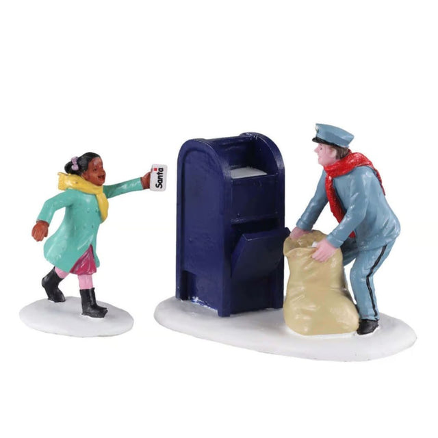 Figurina Lemax con bambina che consegna una lettera per Babbo Natale a un postino accanto a una cassetta postale blu.