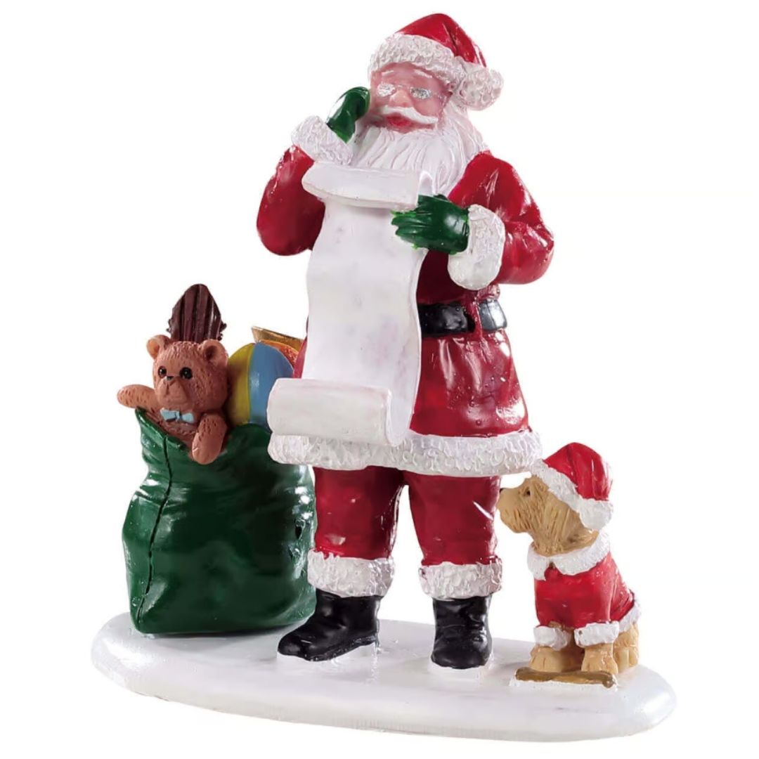 Babbo Natale che controlla la lista dei regali accanto a un sacco verde pieno di giocattoli e a un cagnolino.