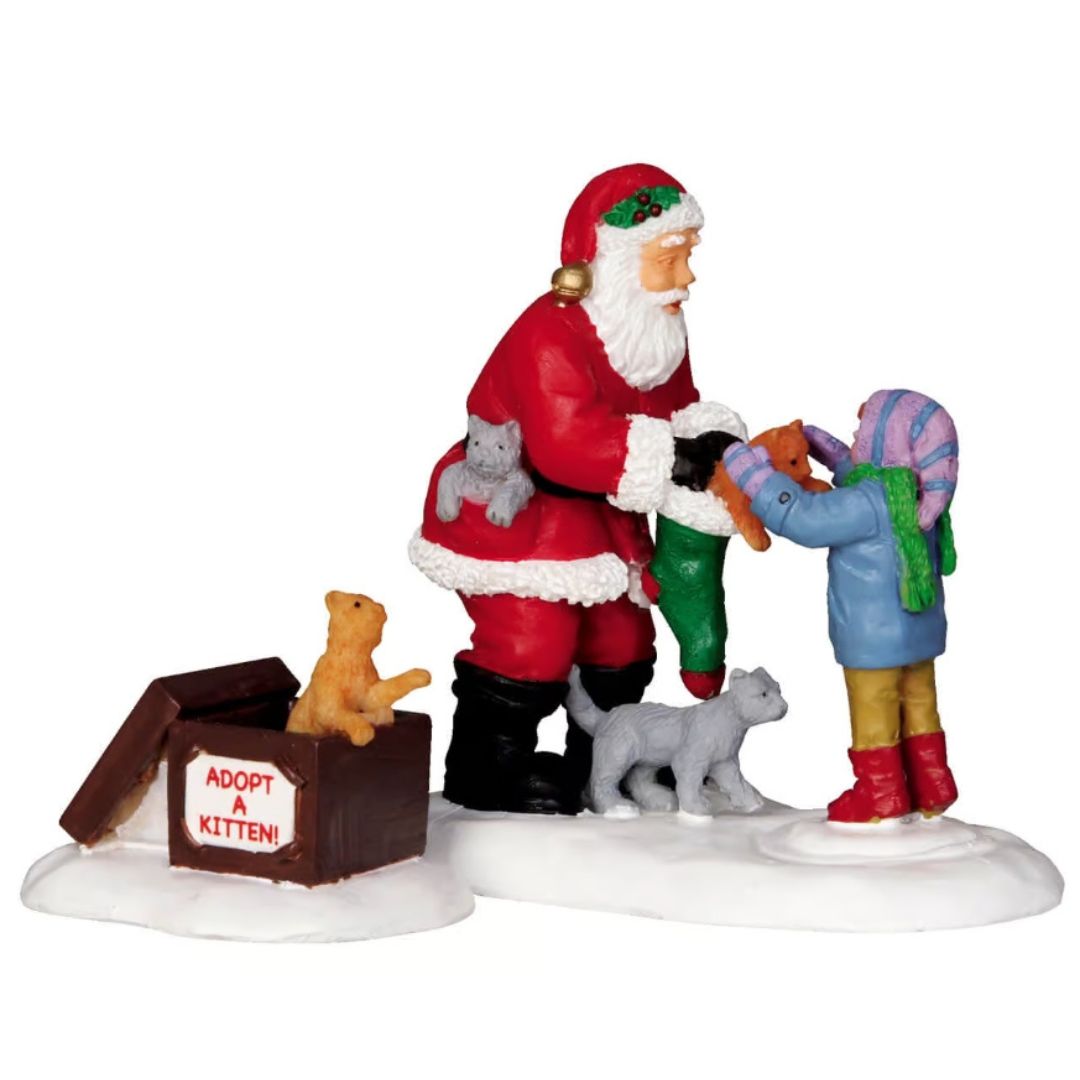 Babbo Natale che consegna un gattino a una bambina, circondato da altri cuccioli e da una cassetta con la scritta “Adopt a Kitten”.