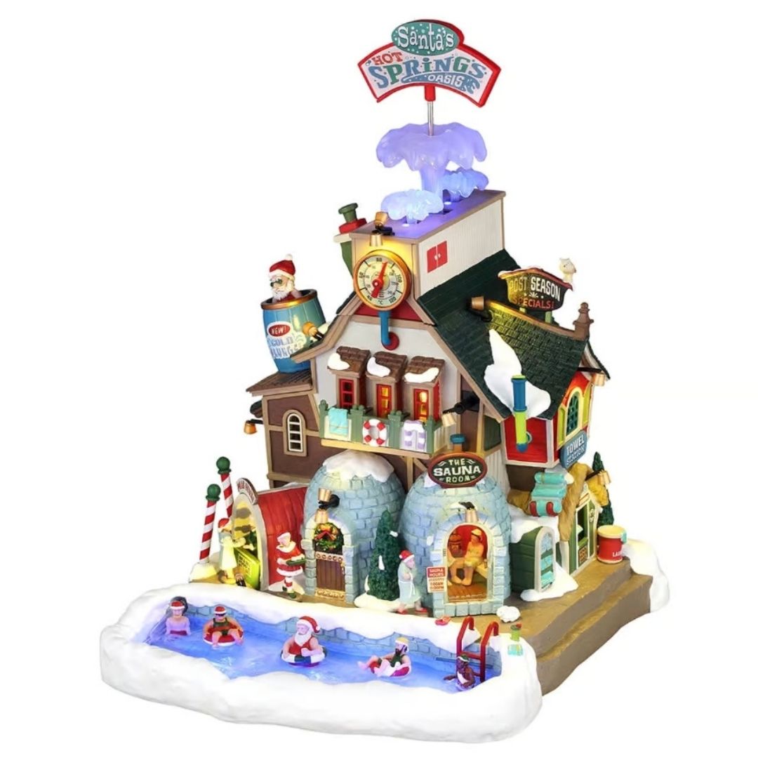 Edificio natalizio Lemax illuminato con centro termale di Babbo Natale, piscina esterna tra la neve, sauna, torre con termometro e dettagli colorati a tema Polo Nord.