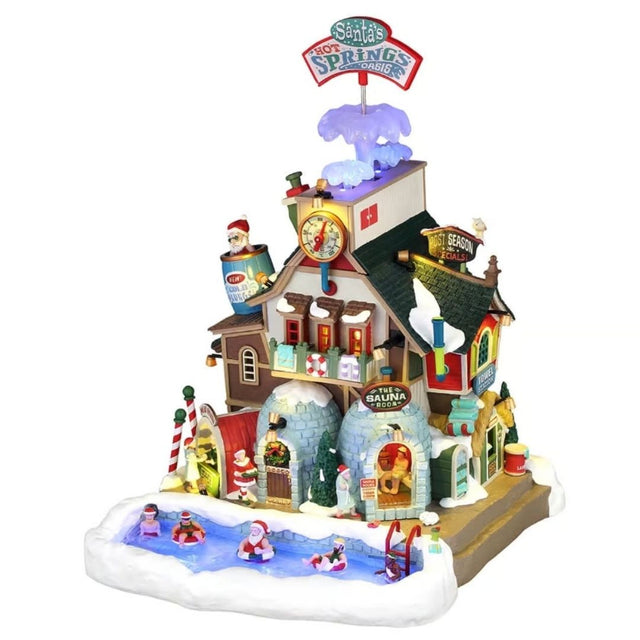 Edificio natalizio Lemax illuminato con centro termale di Babbo Natale, piscina esterna tra la neve, sauna, torre con termometro e dettagli colorati a tema Polo Nord.