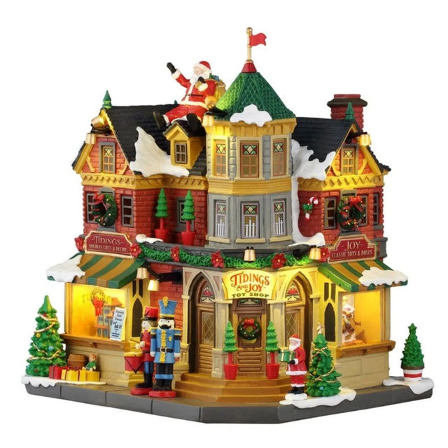 Tidings and Joy Toy Shop Lemax, negozio di giocattoli natalizio illuminato con facciata rossa, vetrine decorate, neve sul tetto, alberelli, schiaccianoci e Babbo Natale.