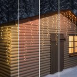Tenda luminosa Ice Light Lotti installata lungo il tetto di una baita in legno innevata, con quattro tonalità di luce calda.