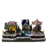 Villaggio natalizio luminoso a tema luna park con giostra, bancarella di popcorn e chiosco del caffè, decorato con luci LED multicolore e personaggi in miniatura.