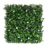 Mattonella di bosso sintetico 50x50 cm con fogliame verde e piccoli fiori bianchi.
