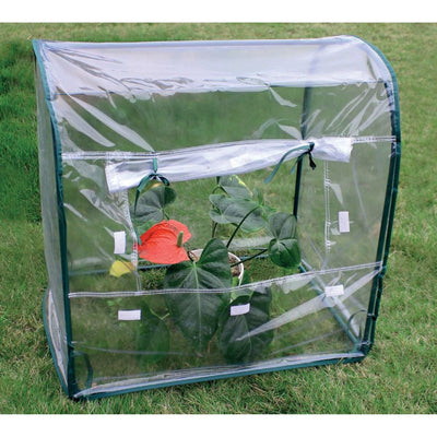 Mini serra da balcone con struttura in metallo e telo trasparente in PVC, posizionata su un prato e contenente piante verdi con un fiore rosso.