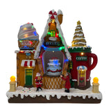 Negozio di dolci natalizio luminoso con casette a tema pasticceria, gelateria e caffè, decorato con luci LED multicolore e figure di Babbo Natale e una bambina.