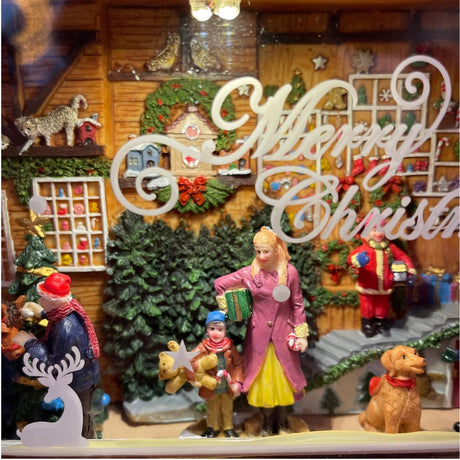 Dettaglio dell'interno del negozio di Natale decorativo con scritta “Merry Christmas”, figure di persone e animali.