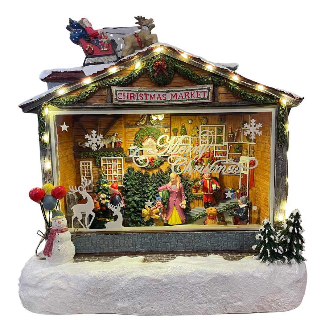 Villaggio natalizio decorativo con insegna “Christmas Market”, figure di persone e animali, decorazioni luminose e slitta di Babbo Natale sul tetto.