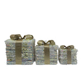Set di tre pacchi regalo decorativi quadrati con led e superficie iridescente con fiocco dorato in tessuto glitterato.