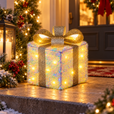 Pacco regalo luminoso da 18 cm con fiocco argentato, posizionato all'ingresso tra ghirlande e luci natalizie