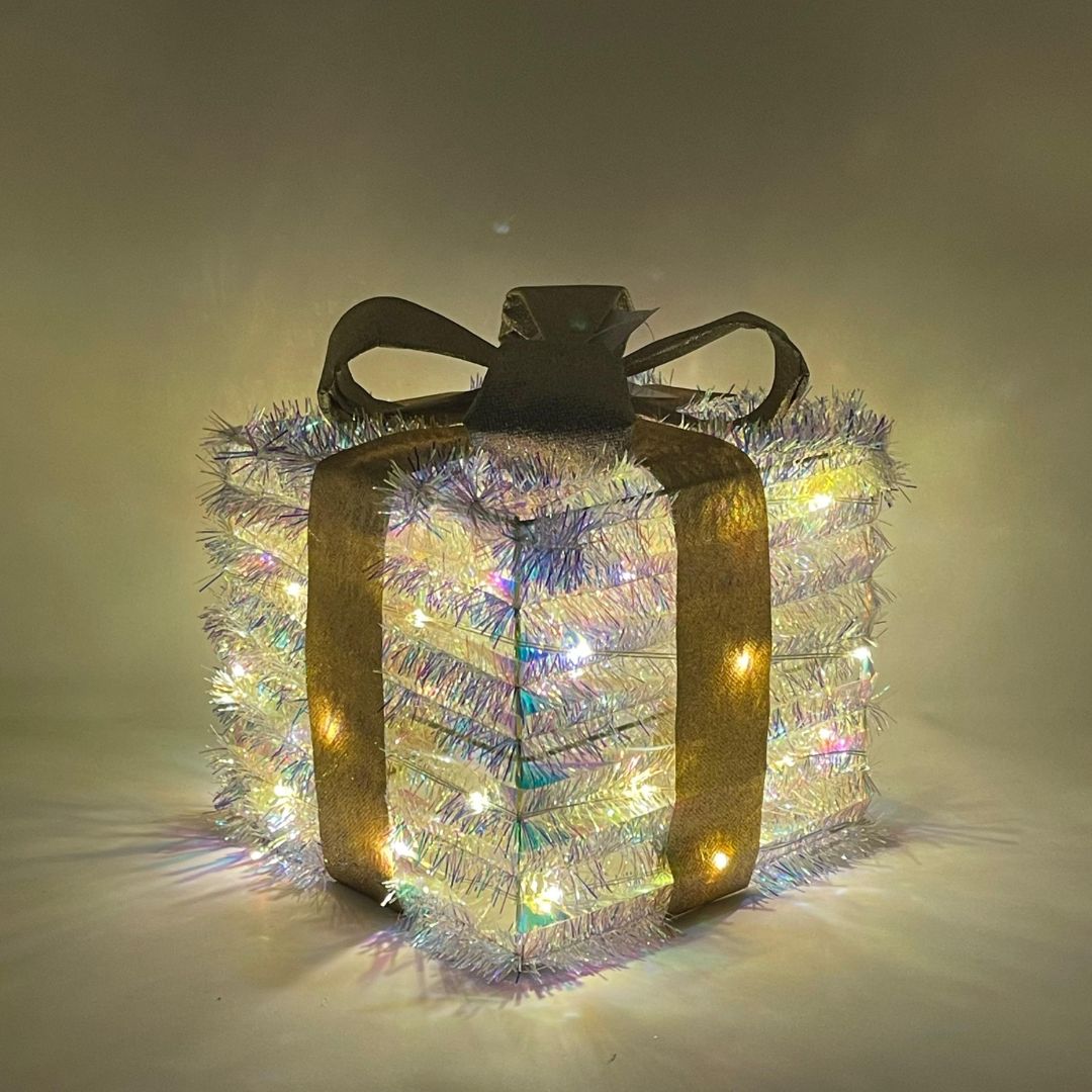Pacco regalo 20cm luminoso quadrato con nastro dorato e luci LED diffuse attraverso la superficie brillante.