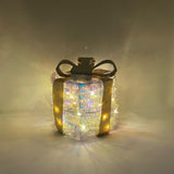 Decorazione luminosa a forma di pacco regalo rotondo con nastro dorato e luci LED.