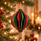 Pallina di Natale decorativa in carta rosso e verde appesa all’albero tra luci calde