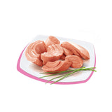 Fettine di tonno rosa su piatto bianco con bordo rosa, guarnito con erba cipollina, ingrediente per cibo umido per gatti.