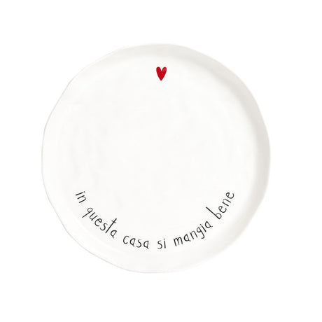 Piatto piano in grès con scritta nera "in questa casa si mangia bene" e cuoricino rosso.