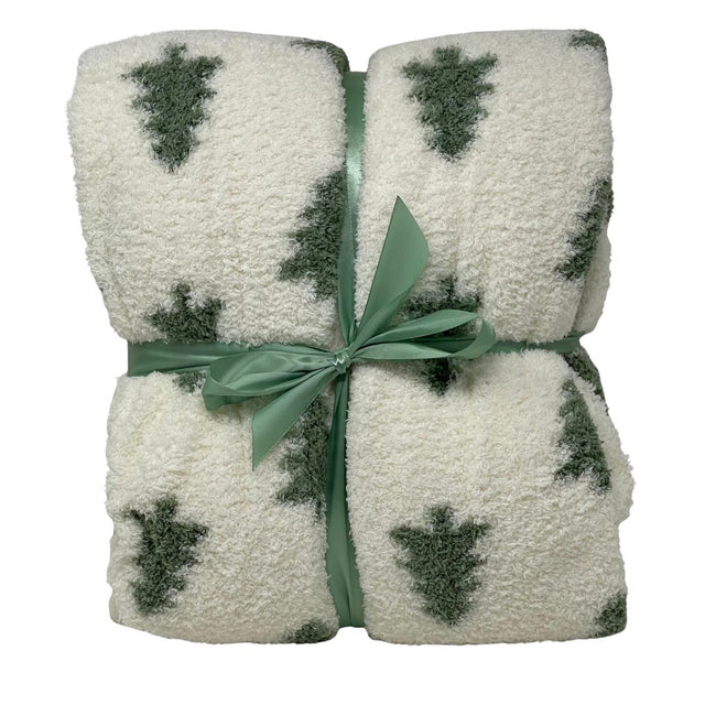 Plaid in tessuto morbido color bianco con motivo di alberelli verdi, piegato e legato con nastro verde.