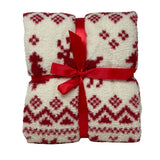 Plaid color bianco con decorazioni rosse a motivi nordici e renne stilizzate, piegato e legato con nastro rosso.