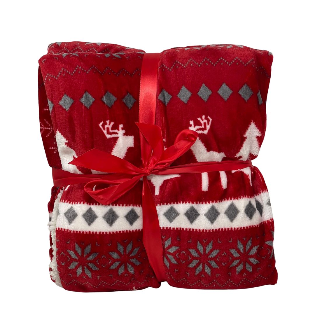 Plaid in pile rosso con decorazioni natalizie bianche e grigie raffiguranti renne, alberi e fiocchi di neve, legato con nastro rosso.