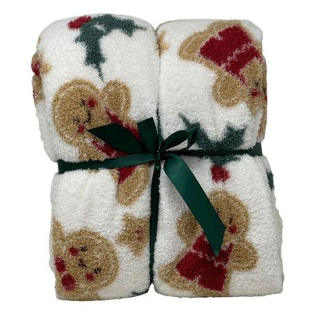 Plaid natalizio in tessuto soffice con disegno di omini pan di zenzero, stelle e agrifogli su fondo bianco, legato con nastro verde scuro.