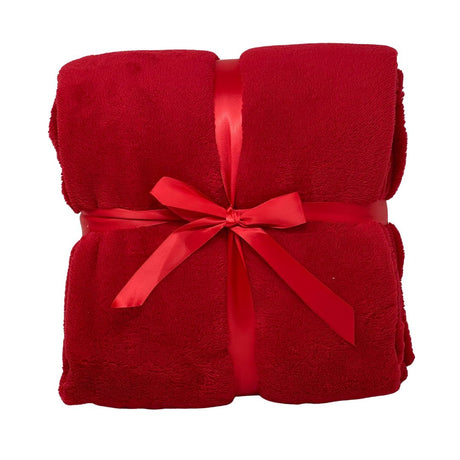 Morbido plaid rosso piegato e legato da un nastro rosso.