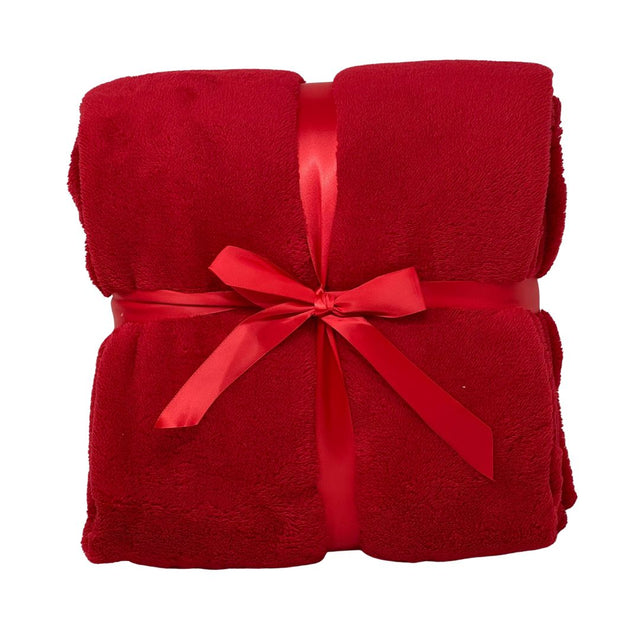 Morbido plaid rosso piegato e legato da un nastro rosso.