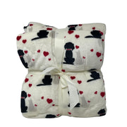 Plaid bianco con stampa di cani neri e beige circondati da cuori rossi, piegato e legato con nastro bianco.