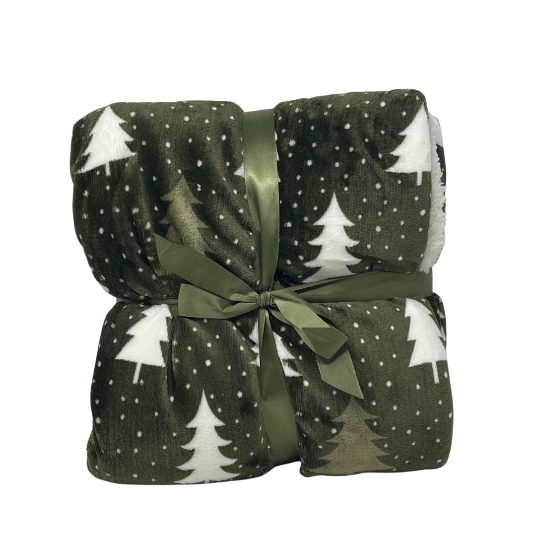 Plaid in pile verde scuro con motivo di alberelli bianchi piegato e legato con nastro verde.