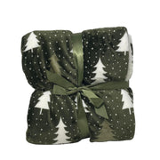 Plaid in pile verde scuro con motivo di alberelli bianchi piegato e legato con nastro verde.