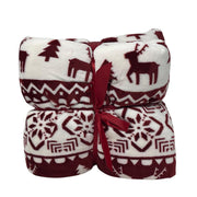 Plaid in pile bianco con disegni natalizi rosso scuro di renne, alberi e motivi geometrici, piegato e legato con nastro rosso.