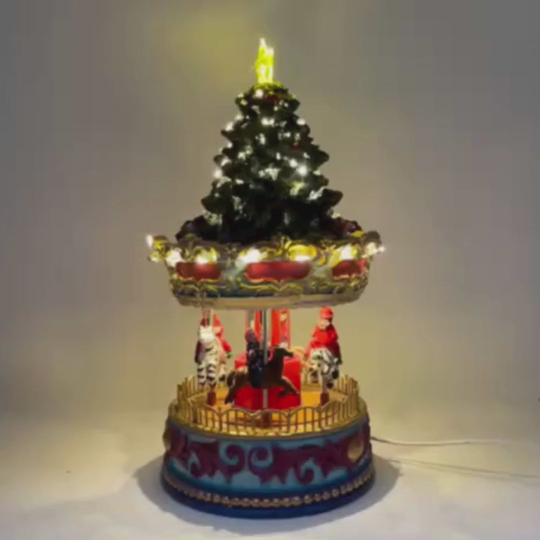 Video della giostra natalizia con cavalli e figure in movimento, sormontata da un albero di Natale decorato con luci LED e stella luminosa sulla cima.
