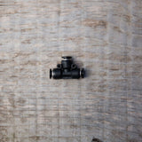 Raccordo a T nero con attacchi rapidi per tubo da 6 mm, posato su superficie in legno chiaro